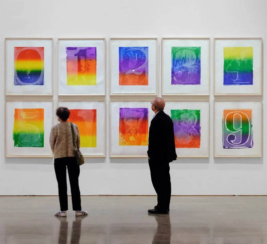 Two people viewing colorful framed abstract number art in a contemporary gallery setting