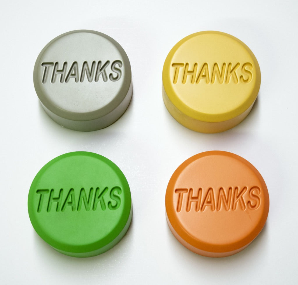 Colorful round tokens embossed with the word THANKS in various pastel and bright colors arranged in rows